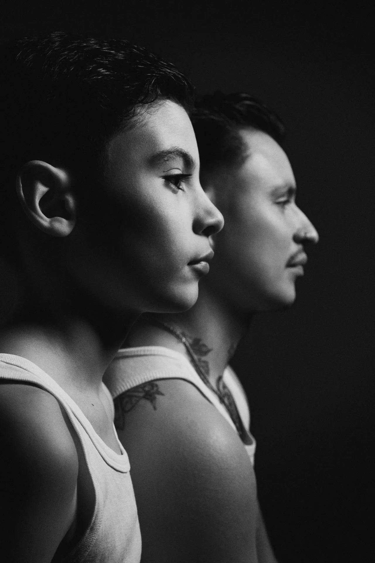 Portrait noir et blanc de deux hommes de profil en débardeur, lumière sombre, Bruxelles