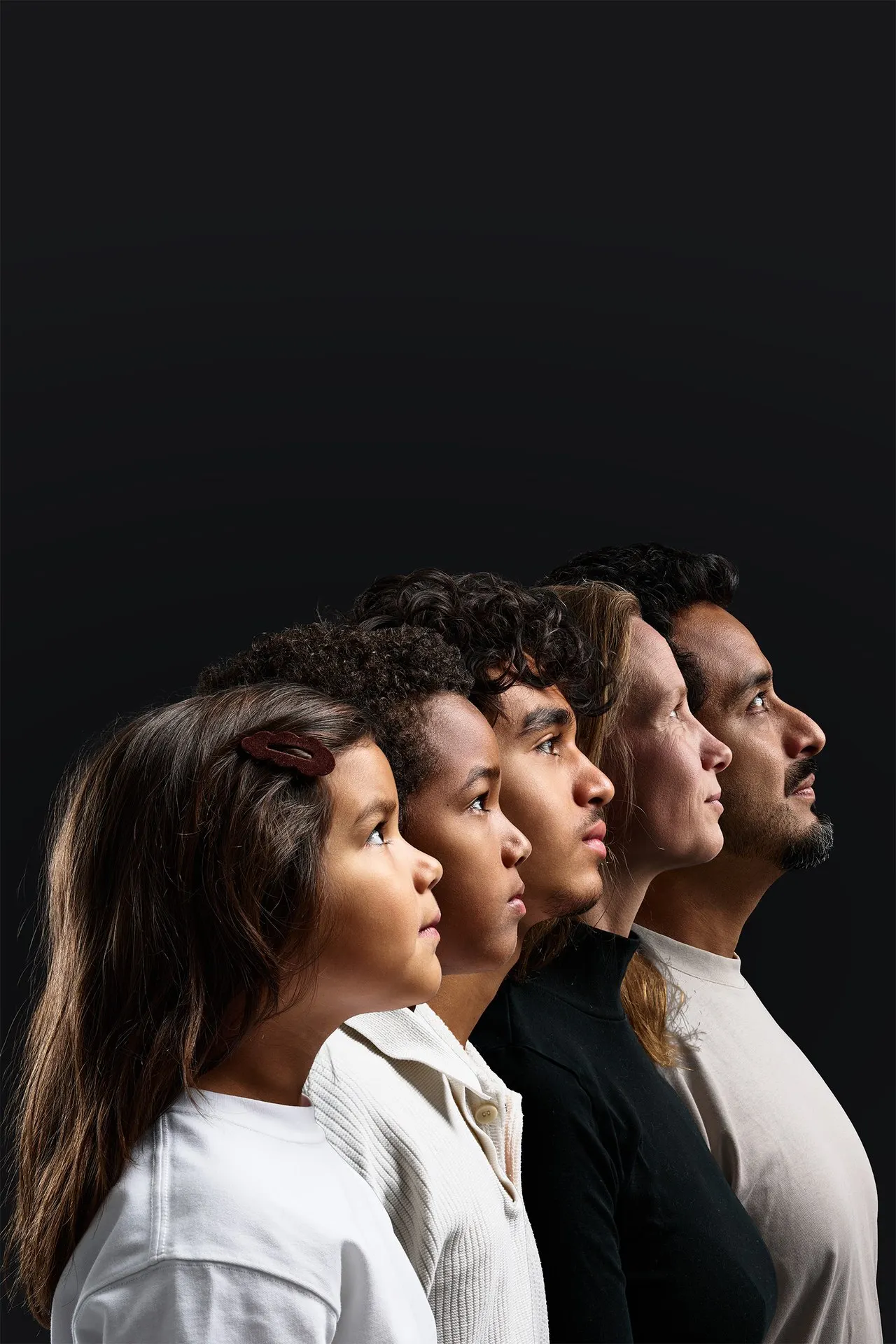 Famille de cinq personnes alignées de profil sur fond sombre, portrait de studio, Bruxelles