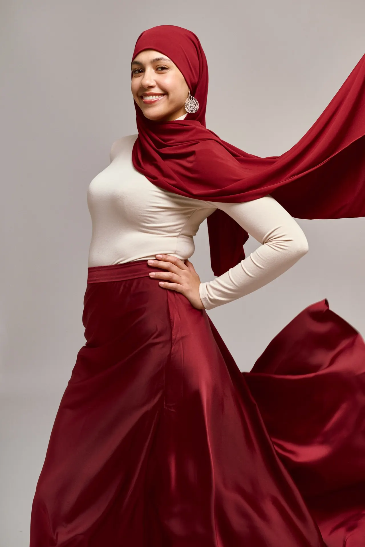 Femme souriante en hijab et jupe rouge en mouvement, studio, Bruxelles