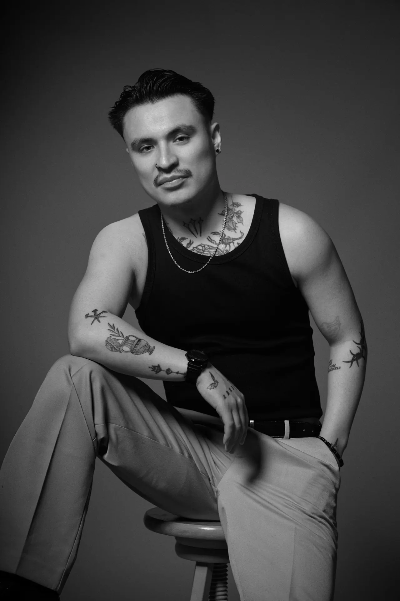 Portrait noir et blanc d'un homme tatoué assis sur un tabouret, studio, Bruxelles